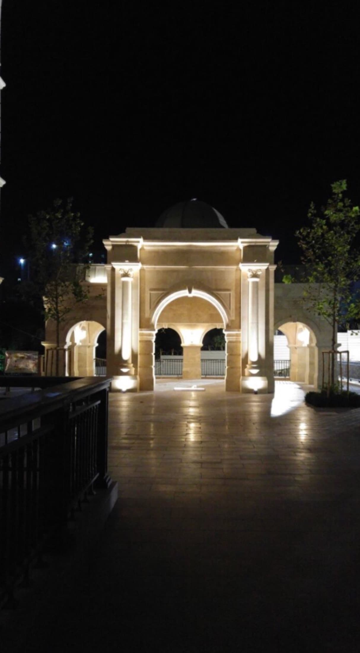 A night view of an arched campus structure, with no people in view.