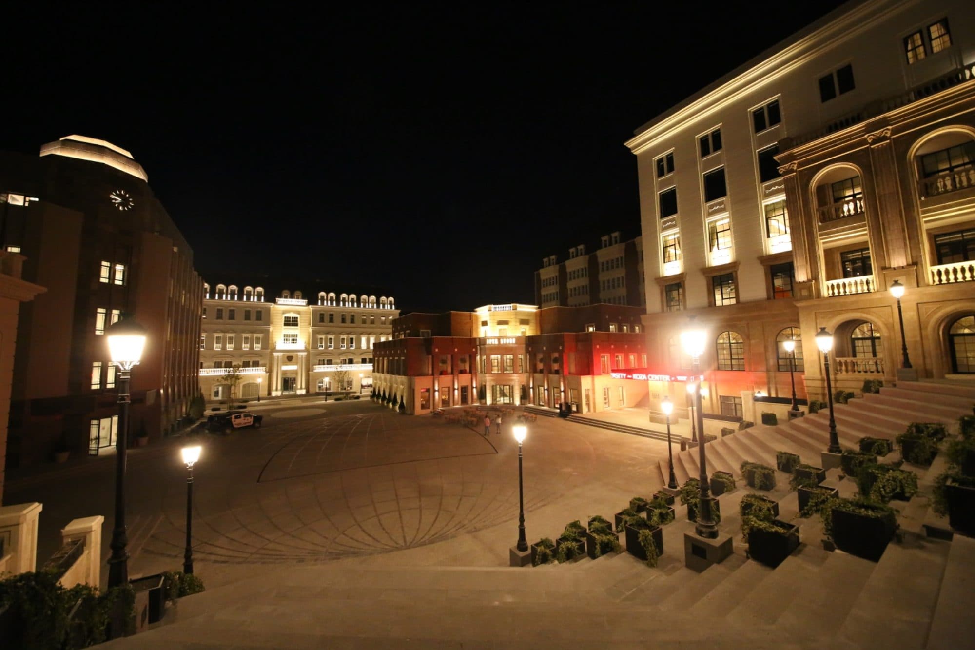 A night view of the campus courtyard from the stairs, with circular pavement and a building marked University Media Center.