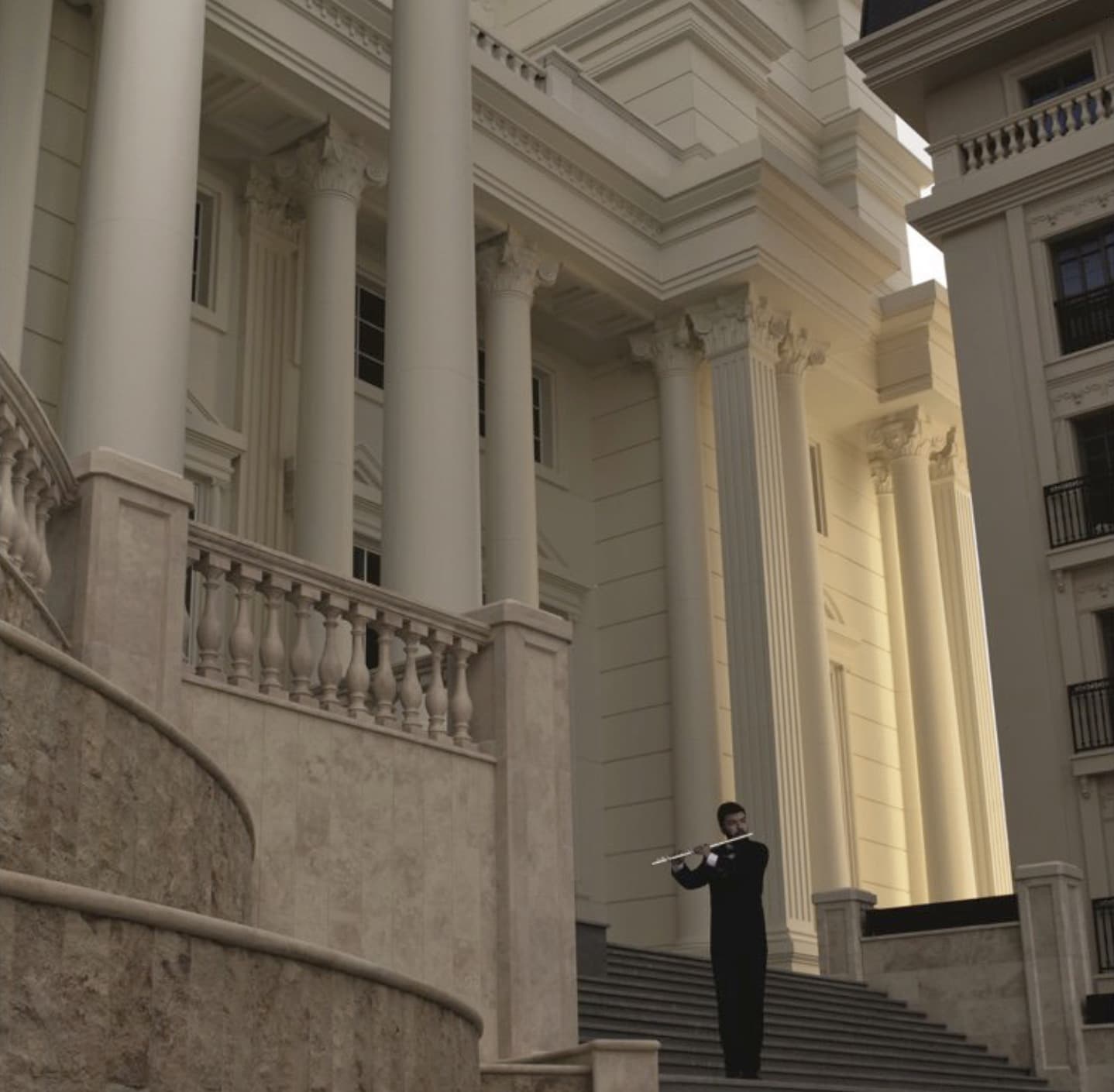 A person playing the flute on campus stairs before classical columns.