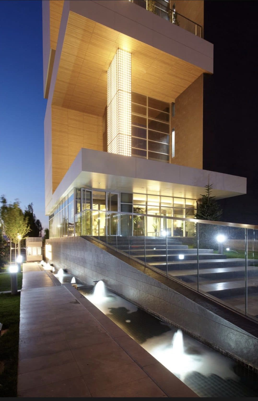 A night view of a contemporary campus building, with stairs and a reflecting pool.