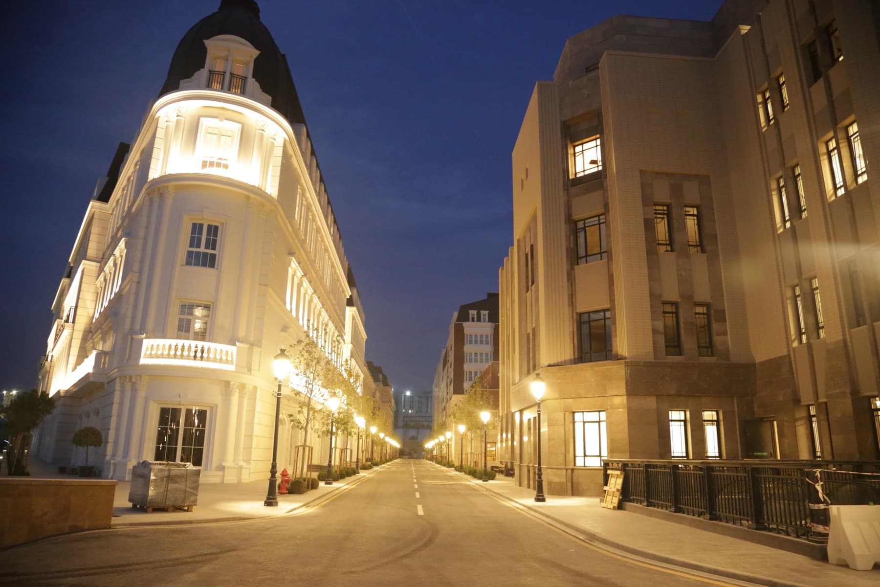 A night view of a campus street, with a white domed building to the left and a stone facade to the right.