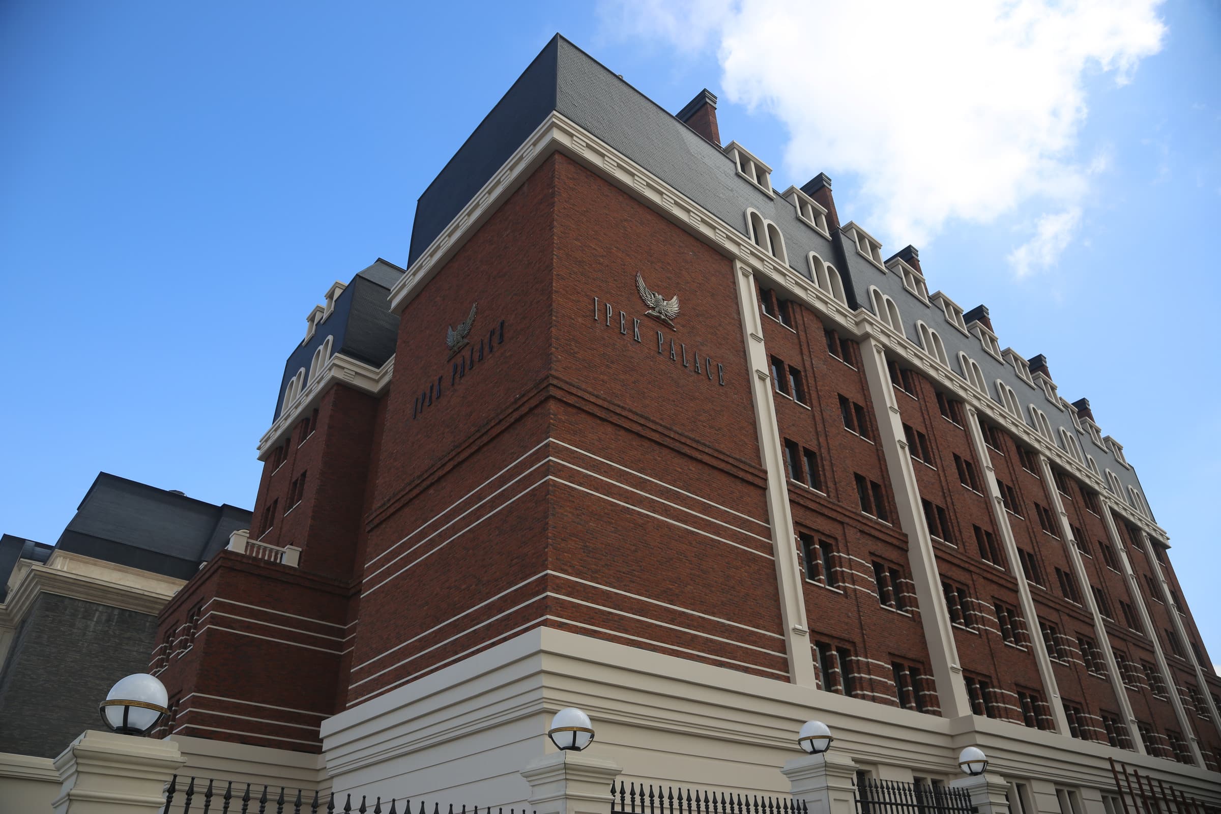 A red-brick campus building inscribed İpek Palace beneath a blue sky.