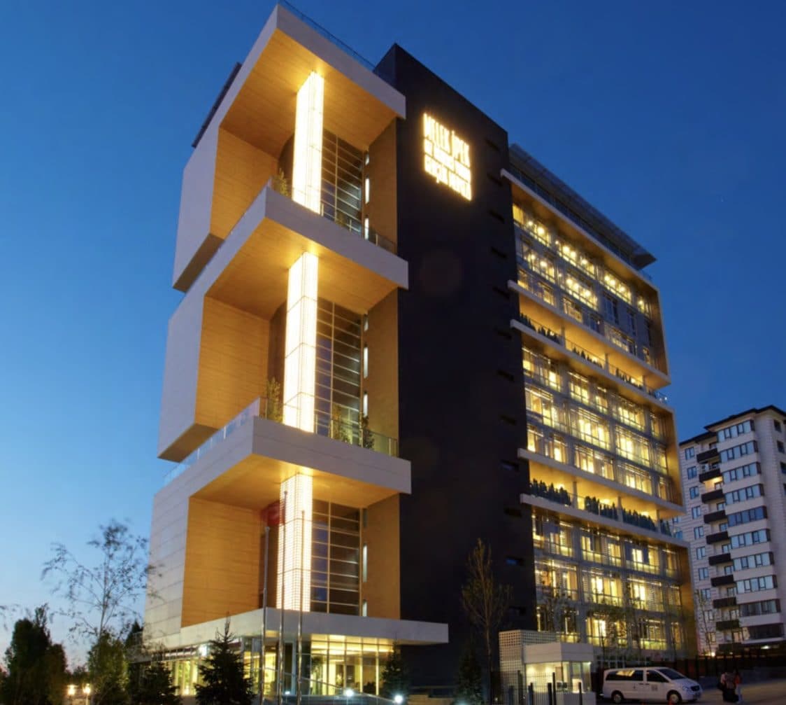 A night view of a campus building whose sign is inscribed Melek İpek Kız Öğrenci Yurdu and Gençlik Merkezi.