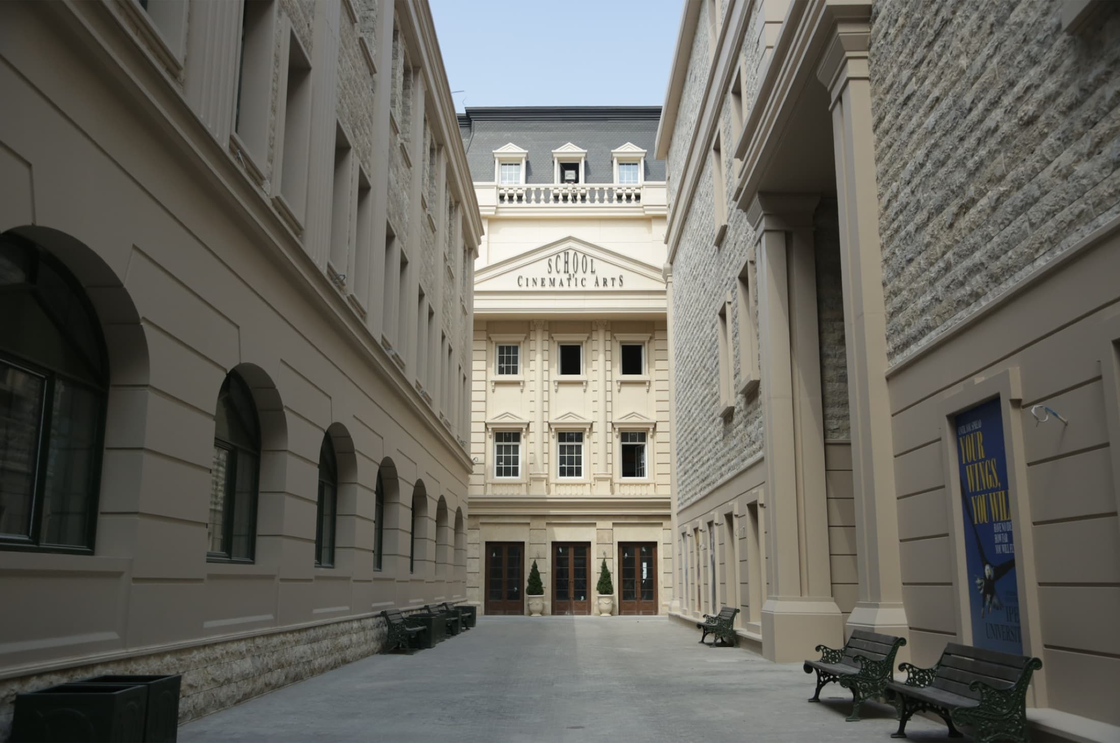 A building seen between two campus facades, its pediment inscribed School of Cinematic Arts.