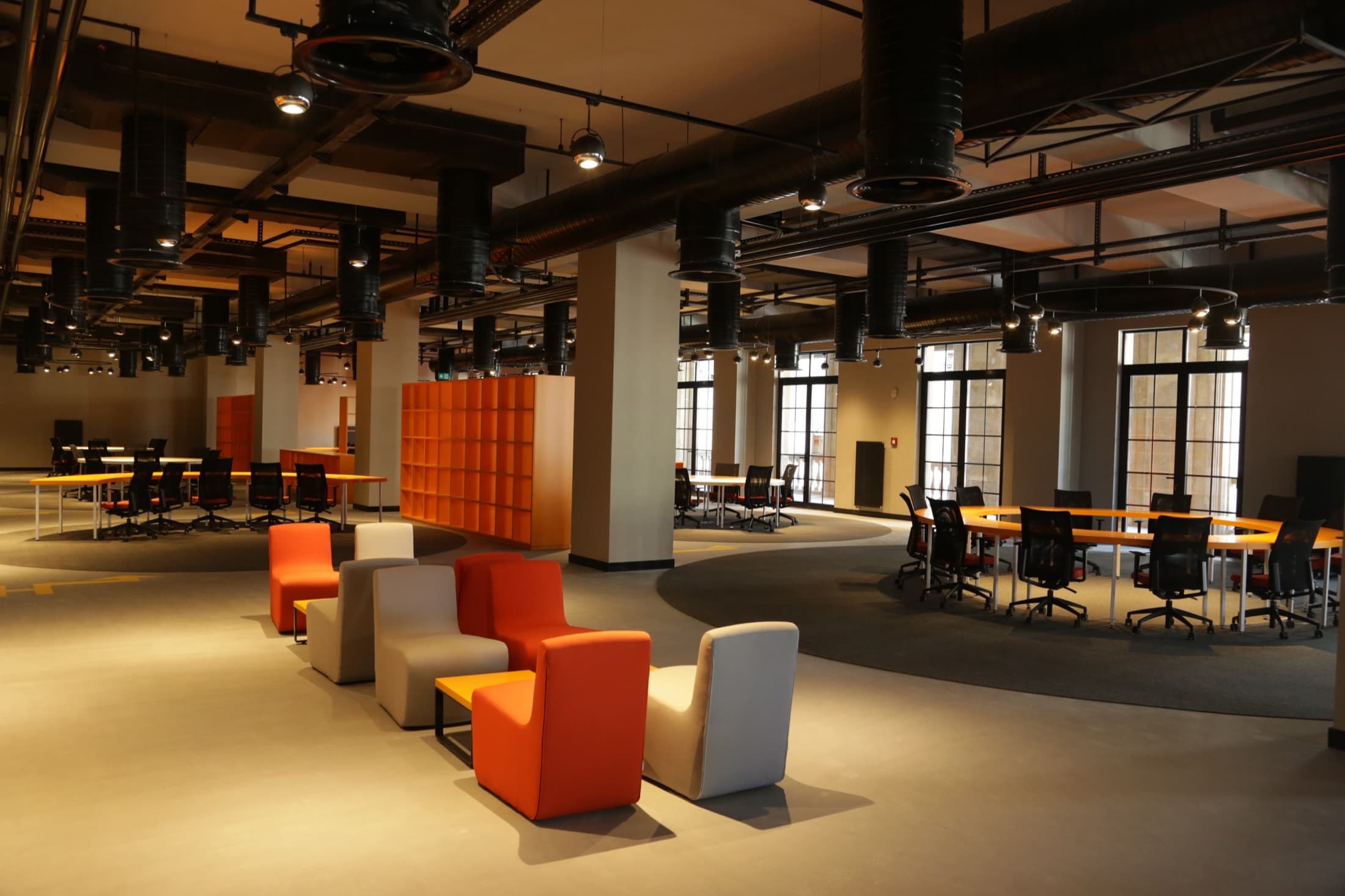 An empty student-club working floor with a high industrial ceiling and no people in view.