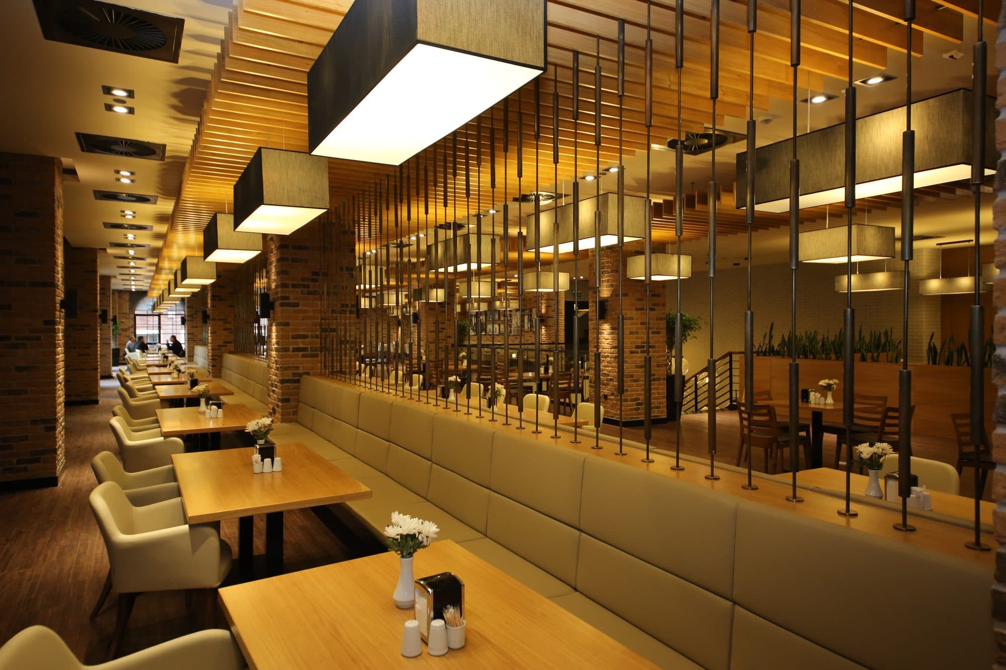 An interior dining space with brick walls and a staircase; the tables are empty.