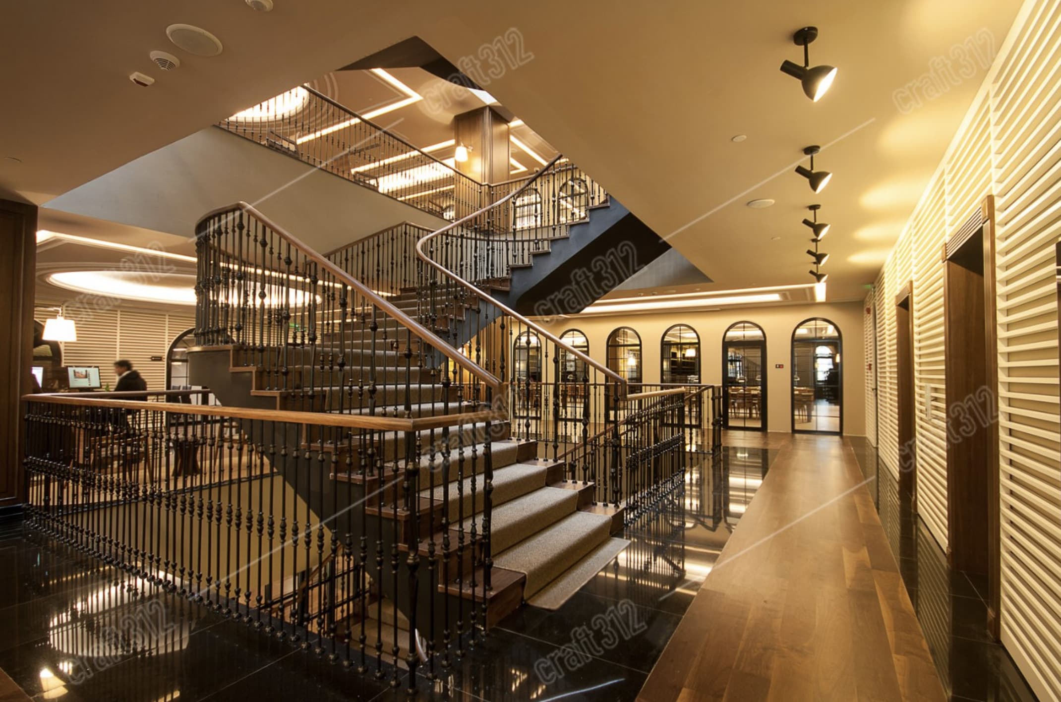 A wide interior staircase with a wooden handrail; a desk is visible to the left.
