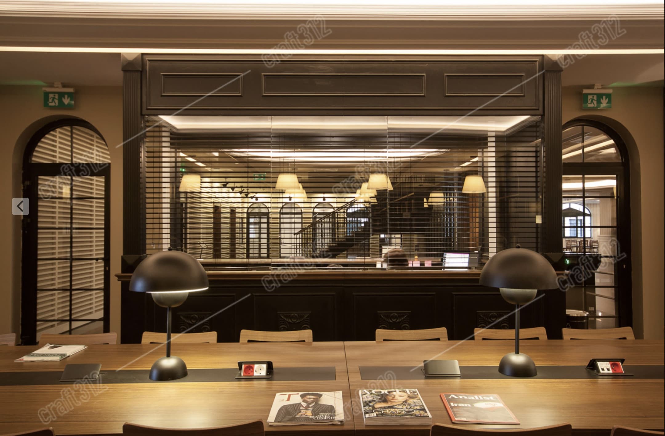 A long study desk with black dome lamps and magazines on the surface.